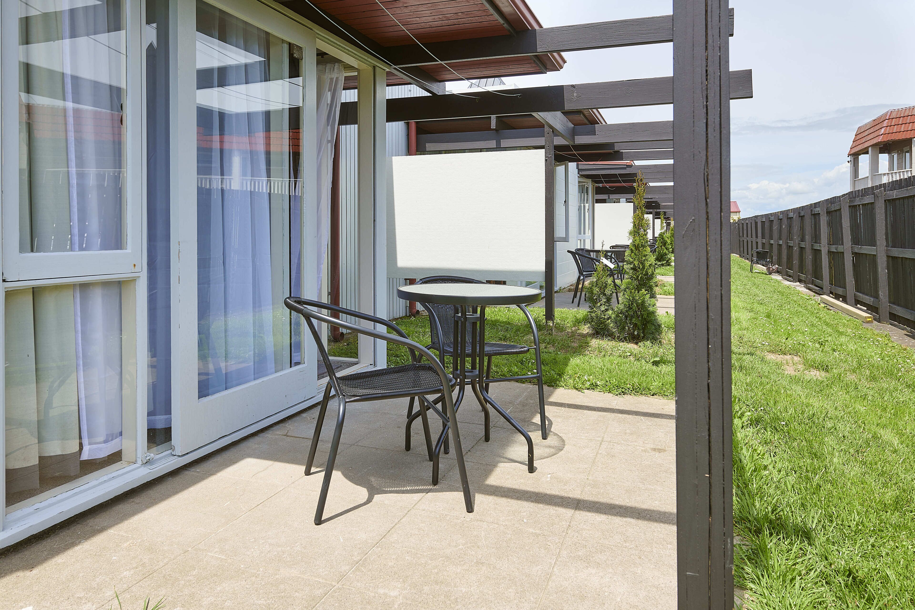Een terras met een tafel en stoelen, een uitzicht op het omliggende landschap en een gebouw met grote ramen.