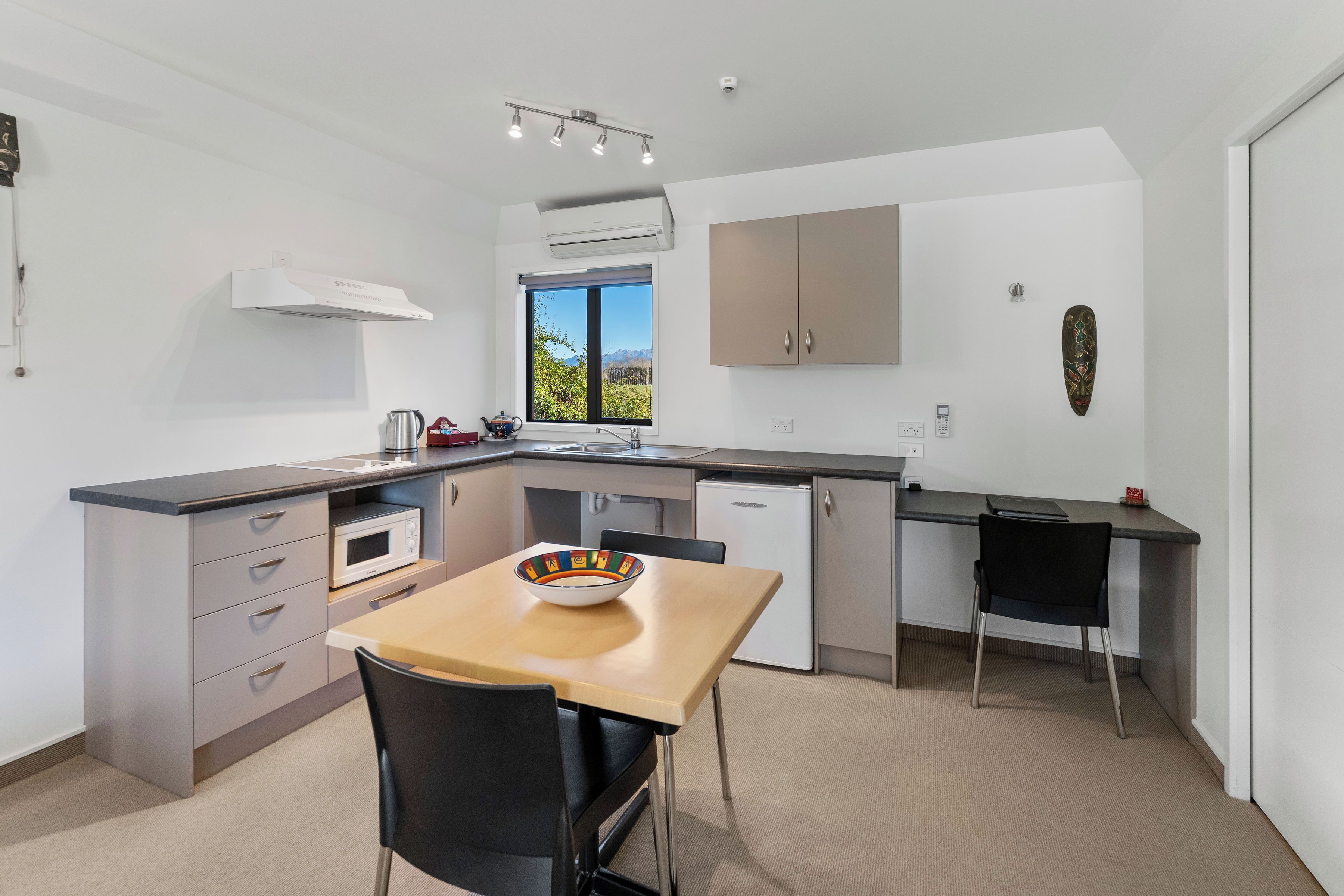 A modern kitchen with a dining area, featuring a microwave, sink, and cabinets.