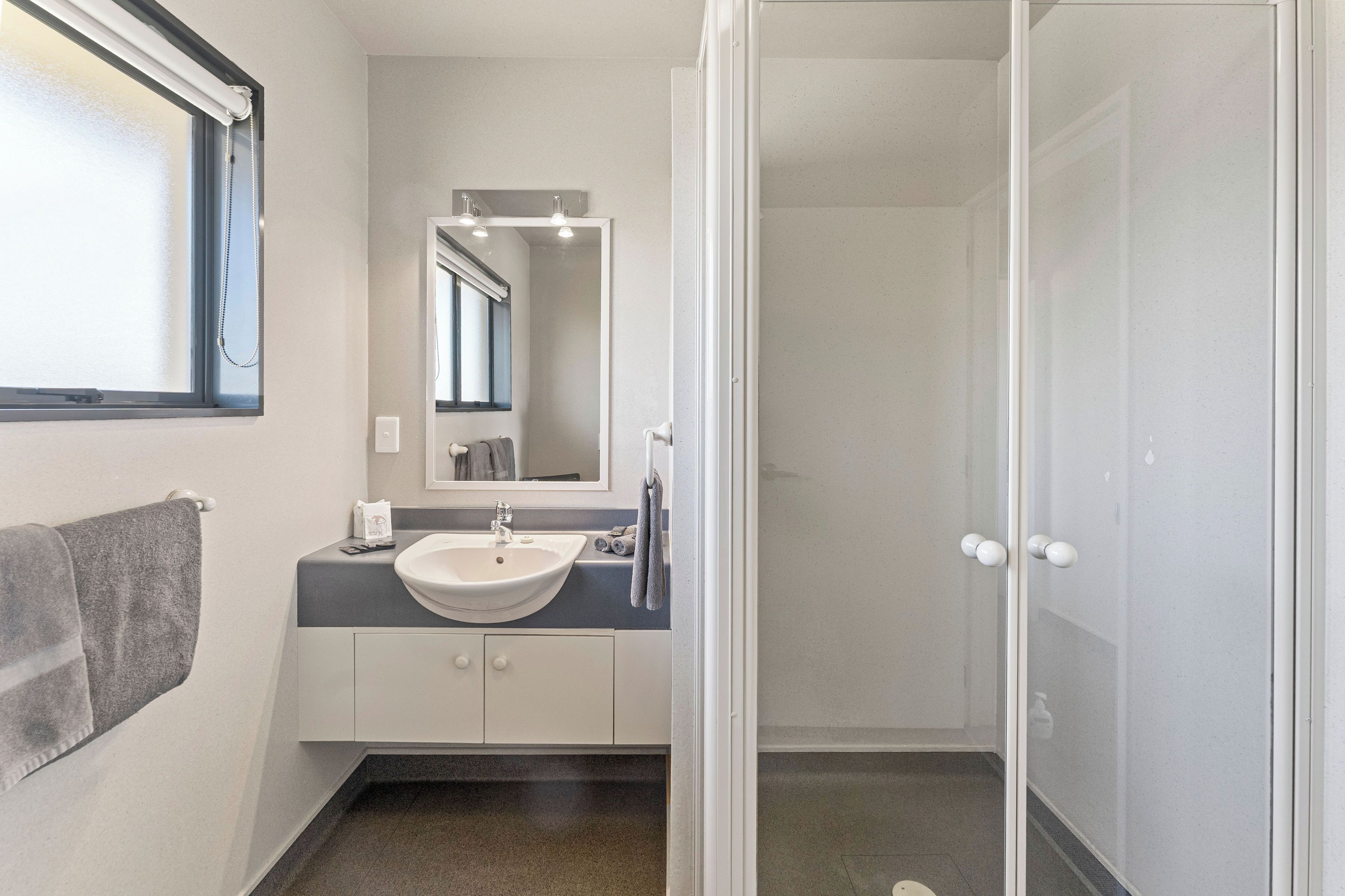 A bathroom with a white sink, a mirror, and a shower door.