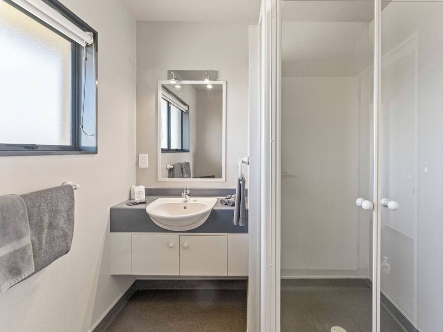 A bathroom with a white sink, a mirror, and a shower door.