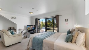 A modern hotel room with a large bed, a sofa, a television, and a balcony with a view of the outdoors. - Avalon Manor Motel (Motueka)