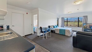 A modern hotel room with a kitchenette, a dining area, a bed with a view, and a sofa. - Avalon Manor Motel (Motueka)