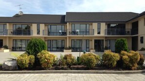 A two-story building with balconies, large windows, and a paved courtyard. - Avalon Manor Motel (Motueka)