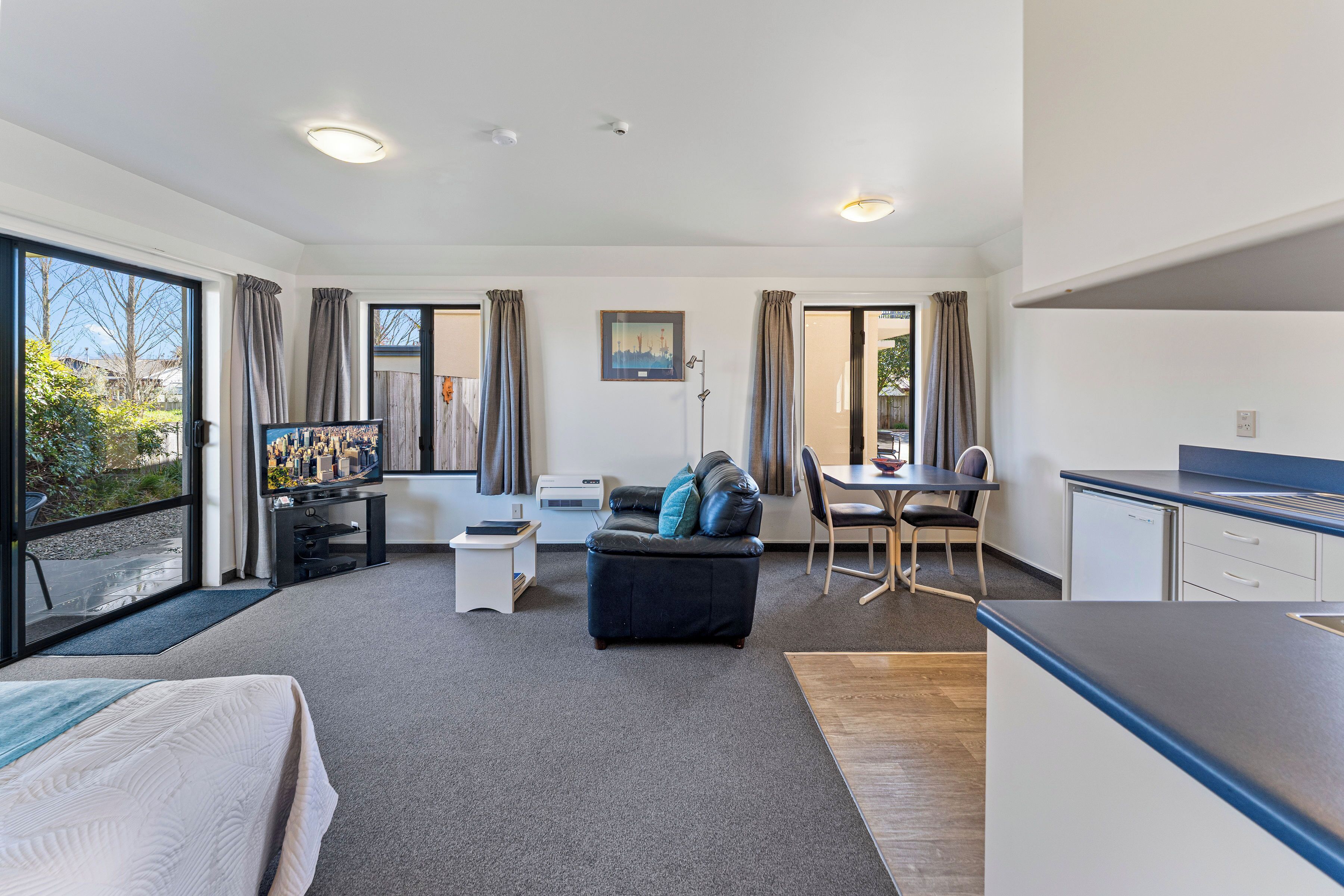 Una habitación de hotel moderna con una cama grande, un sofá, un comedor y un rincón de cocina.