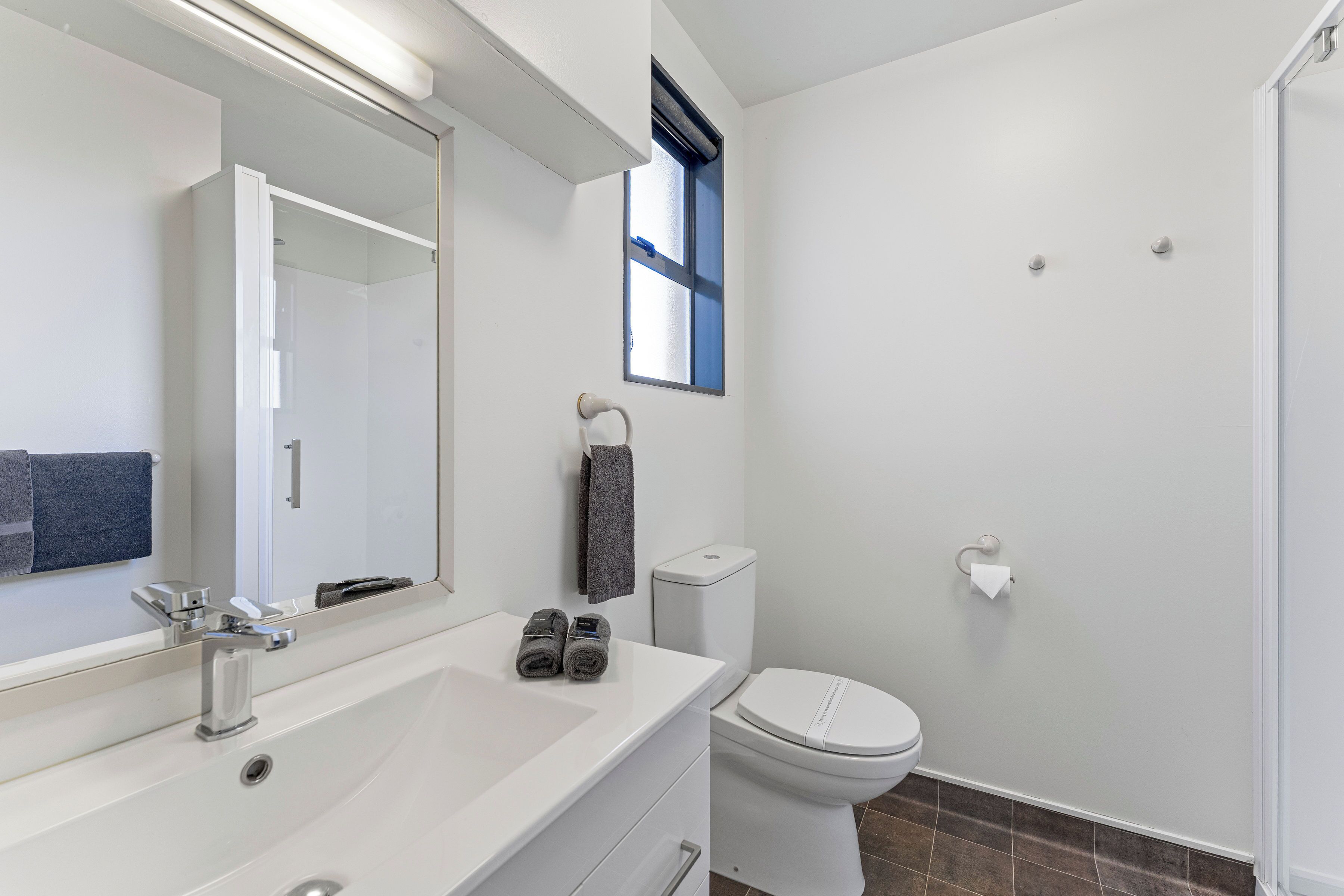 Une salle de bain moderne avec un lavabo blanc, un miroir et des toilettes.