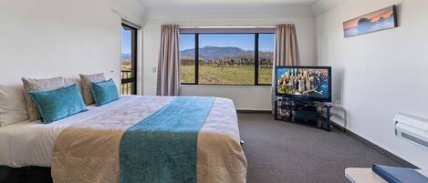 A hotel room with a large bed, a television, and a view of the outdoors.