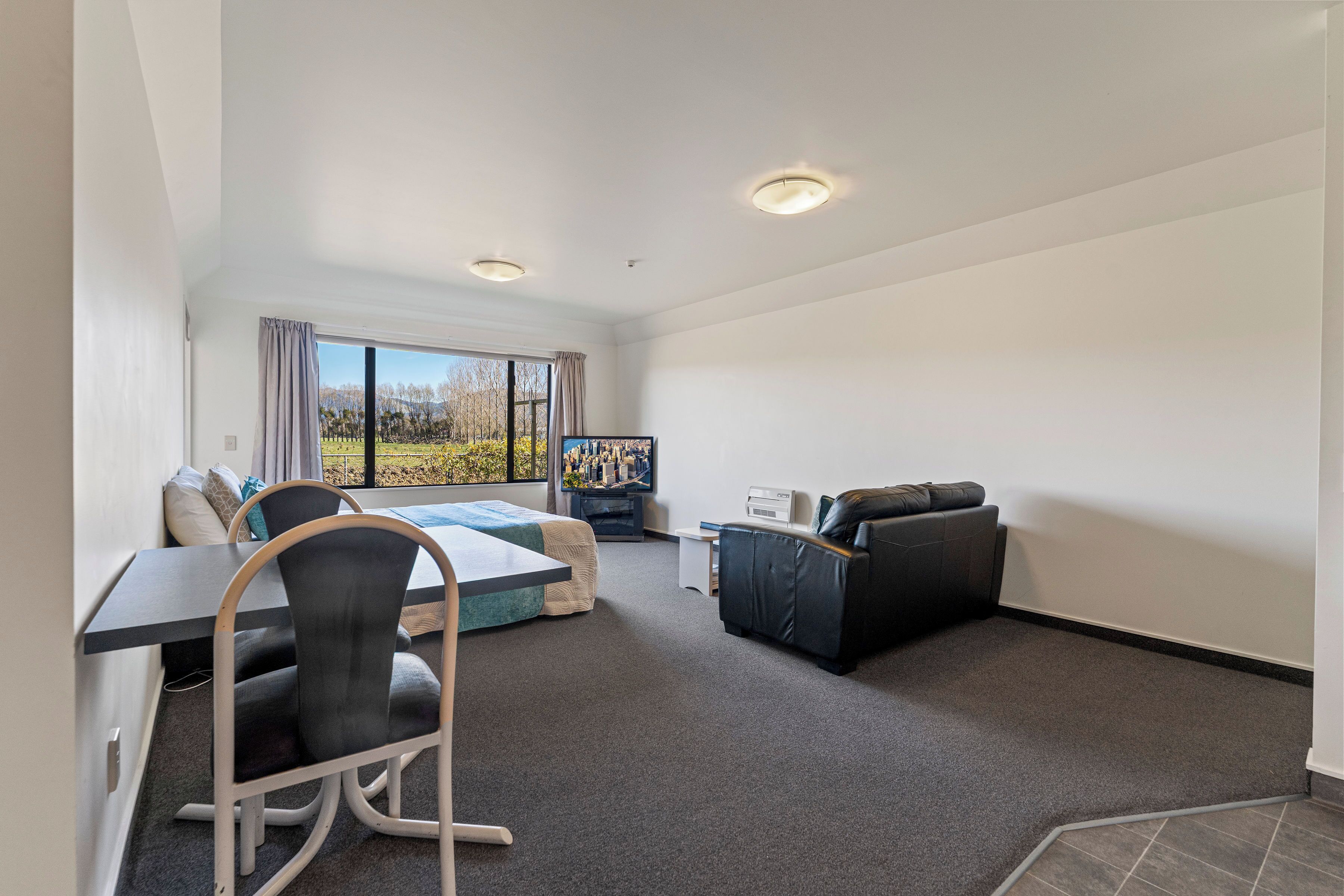 Une chambre d’hôtel moderne équipée d’un lit, d’un bureau, d’une chaise, d’un canapé et d’une télévision.