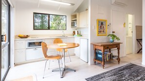 A modern kitchen with white cabinets, a dining table with chairs, a microwave, and a large window.