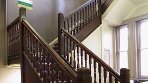 A wooden staircase with a handrail, carpeted steps, and a "No Smoking" sign on the wall. - The George Sydney - Hostel (Haymarket)
