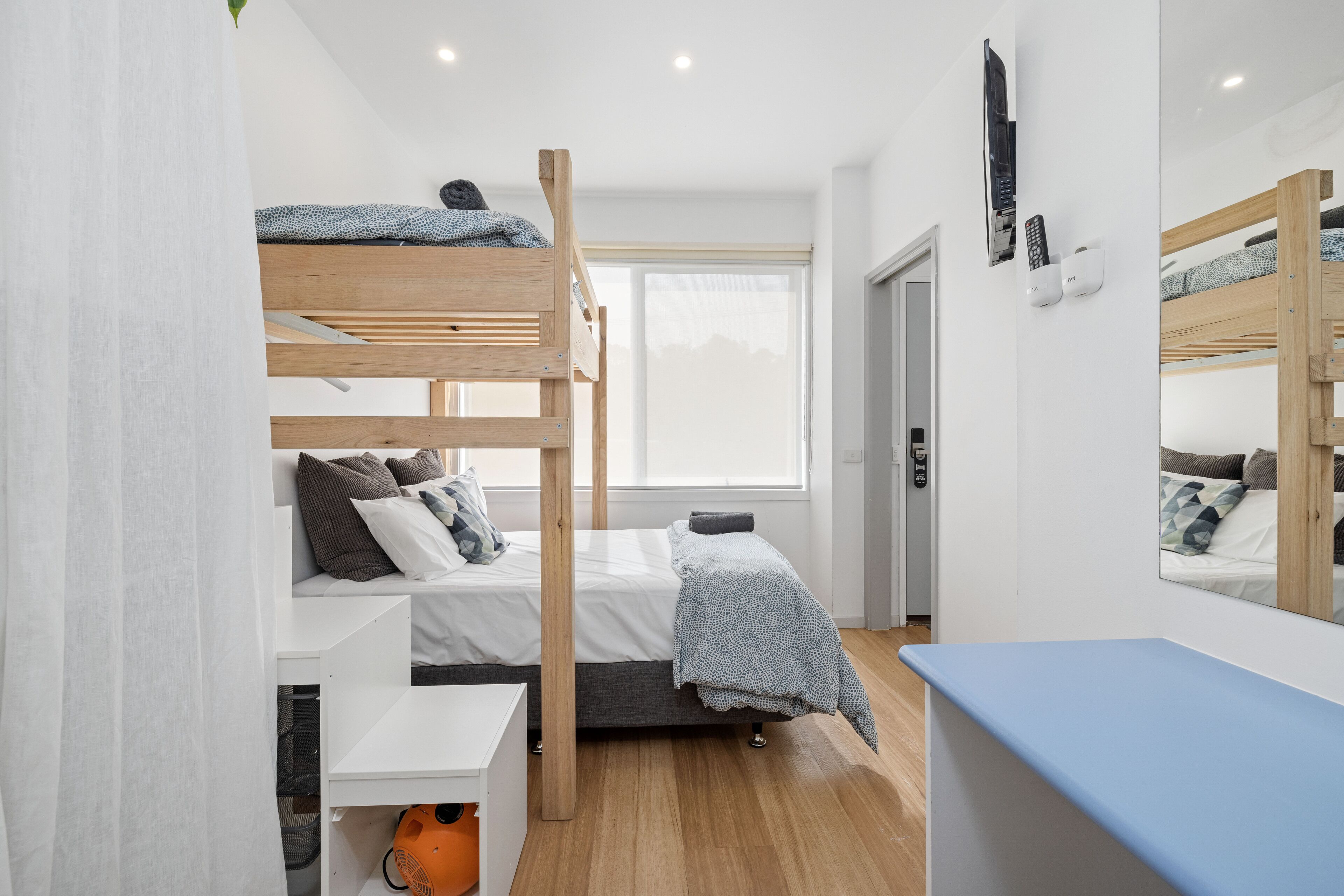 Una habitación moderna y bien iluminada con literas, un escritorio y un espejo grande.