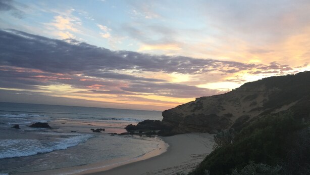 A coastal landscape with a beach, rocky cliffs, and a sunset sky. - Moody's Motel (Blairgowrie)