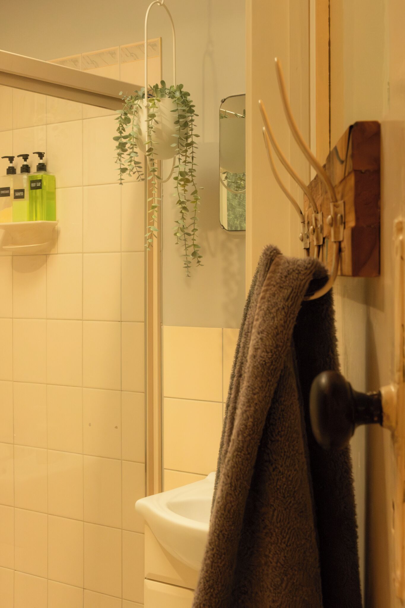 A bathroom with a shower, a sink, a towel rack, and a mirror.