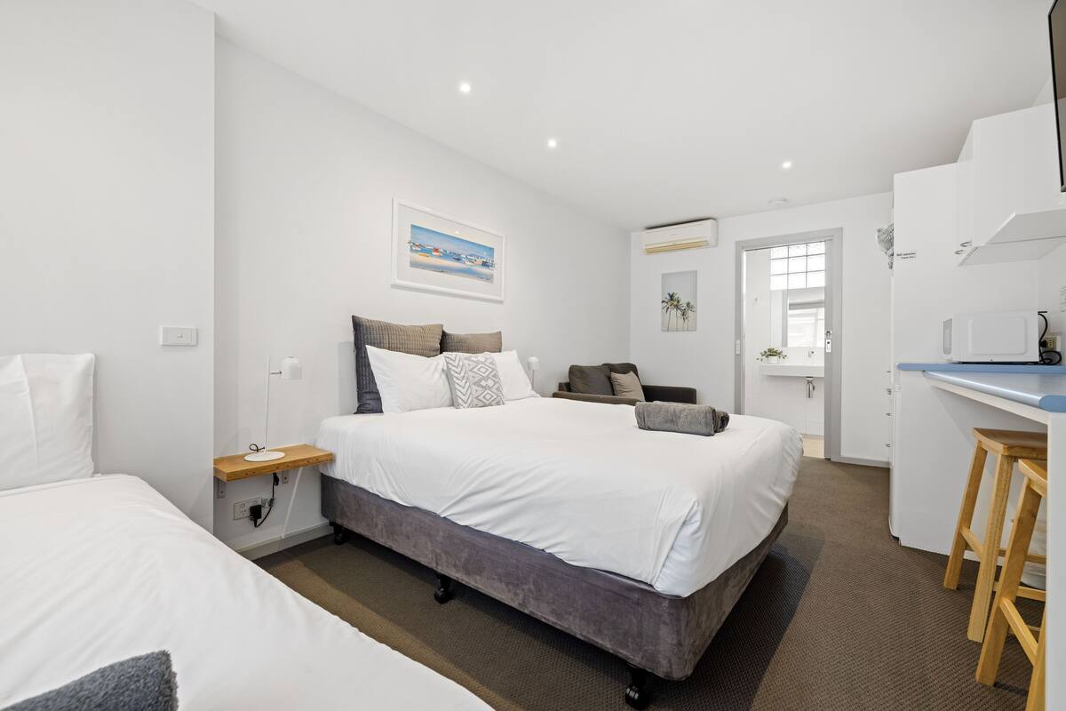 Quarto de hotel moderno com uma cama grande, uma escrivaninha e vista para a cidade.