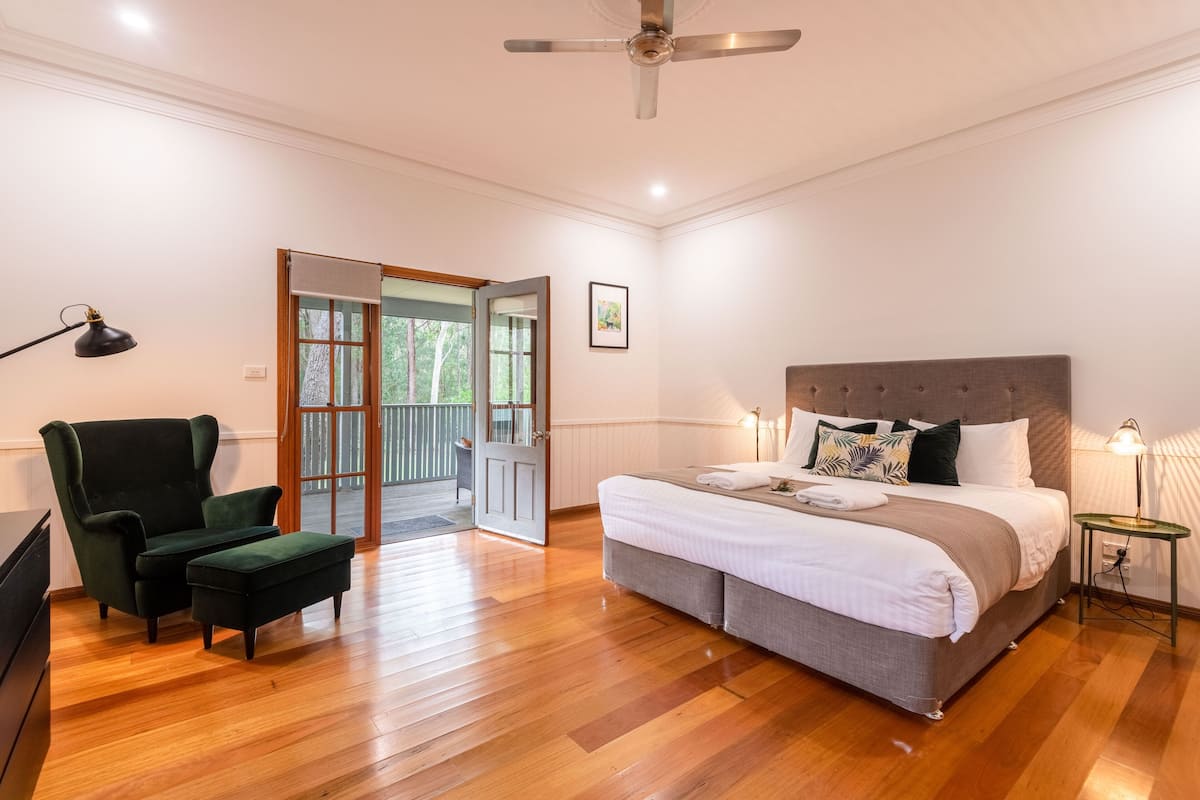 A bedroom with a large bed, a chair, a desk, and a ceiling fan.