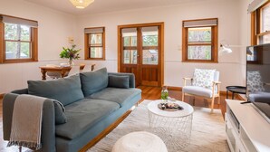 A living room with a sofa, a coffee table, a TV, and a chair. - Bay and Bush, Jervis Bay (Woollamia)