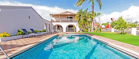 Una piscina al aire libre, sombrillas, sillones reclinables de piscina