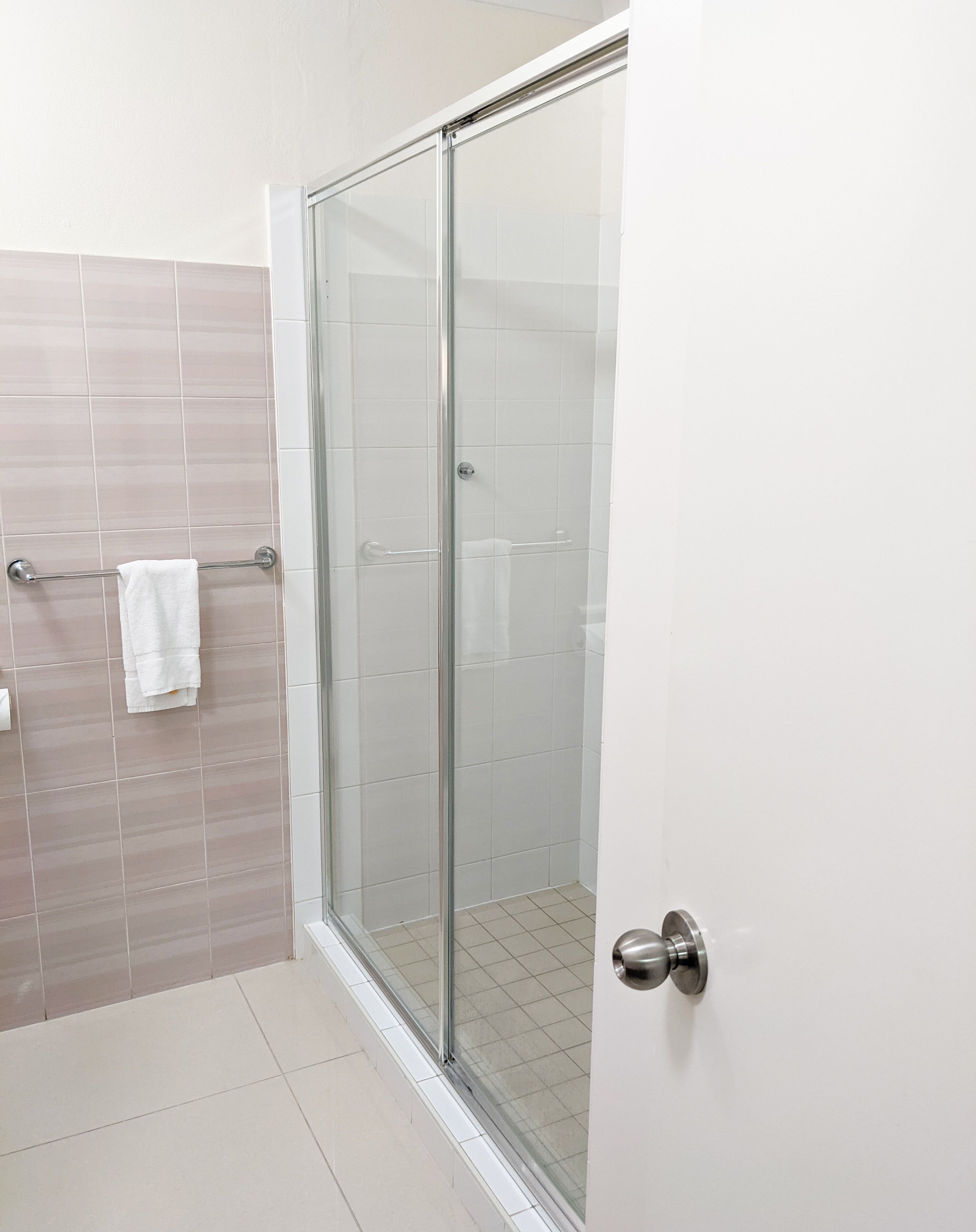 A modern bathroom with a glass shower enclosure, a towel rack, and a toilet.