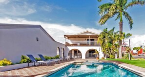 A two-story building with a pool, outdoor seating, and palm trees. - Casa Nostra Motel Mackay (West Mackay)