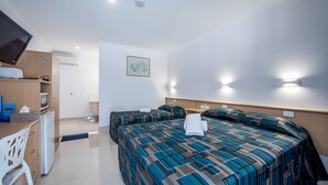 A hotel room with two beds, a desk, a television, and a small kitchenette. - Casa Nostra Motel Mackay (West Mackay)