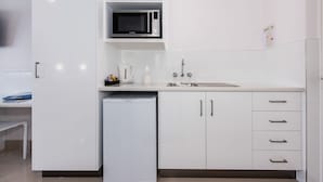 A modern kitchen with white cabinets, a microwave, a coffee maker, and a dishwasher. - Casa Nostra Motel Mackay (West Mackay)