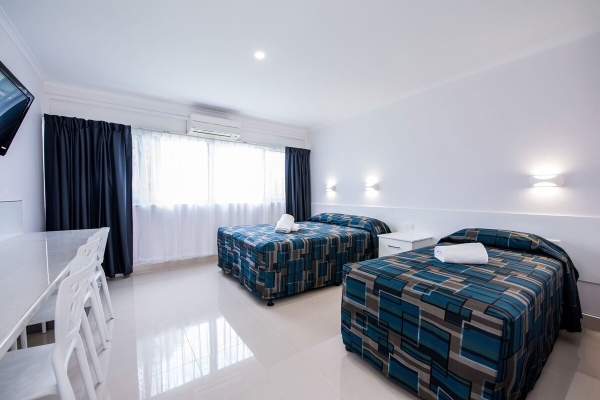 Habitación de hotel con dos camas, un escritorio y una silla.