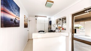 A modern kitchen with white cabinets, a countertop, and a view of the street. - Casa Nostra Motel Mackay (West Mackay)