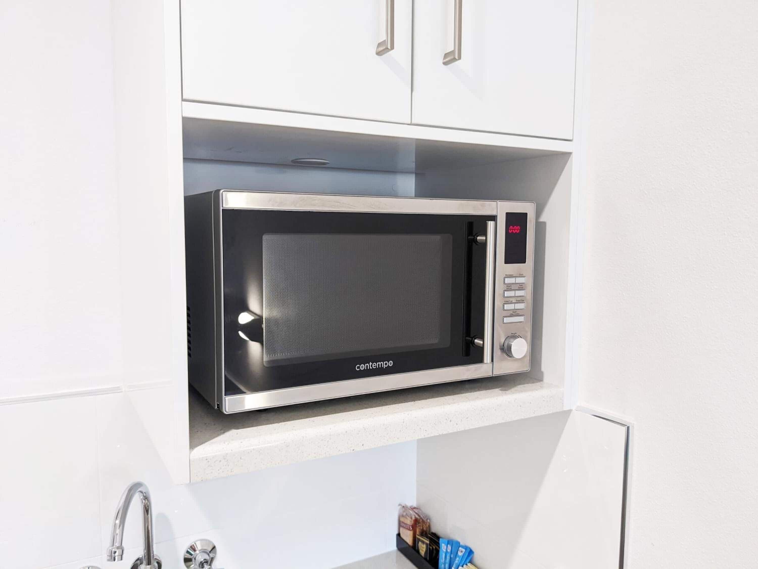 A compact microwave in a kitchen cabinet.