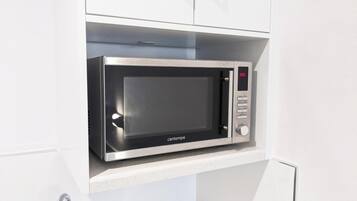 A compact microwave in a kitchen cabinet.