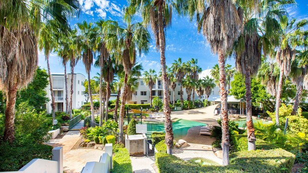 A resort with palm trees, a pool, and a pathway leading to a building. - Bridgewater Terraces (Kangaroo Point)