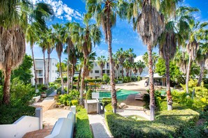 A resort with palm trees, a pool, and a pathway leading to a building.