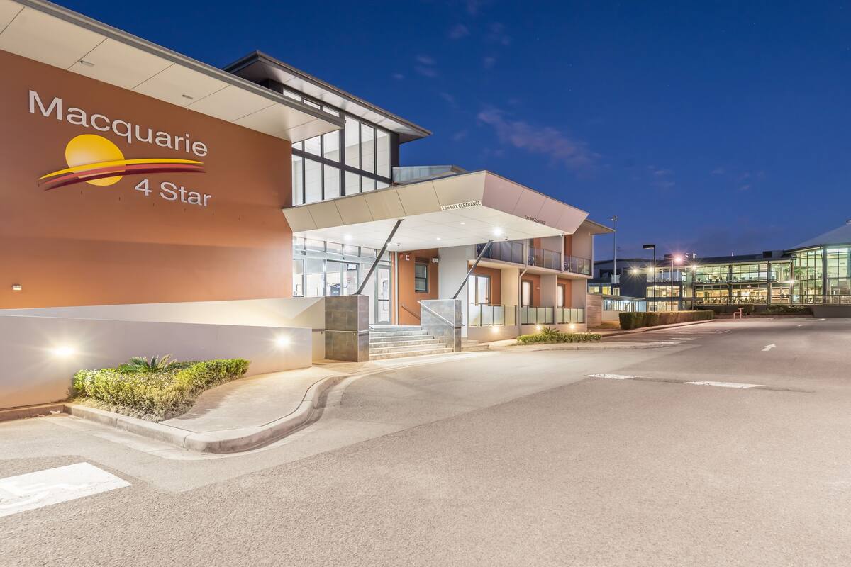 A modern hotel exterior with a 4-star rating, a covered entrance, and a well-lit pathway.