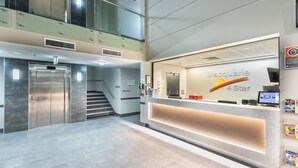 A hotel reception area with a modern design, including a reception desk, elevators, and a staircase. - Macquarie 4 Star (Argenton)