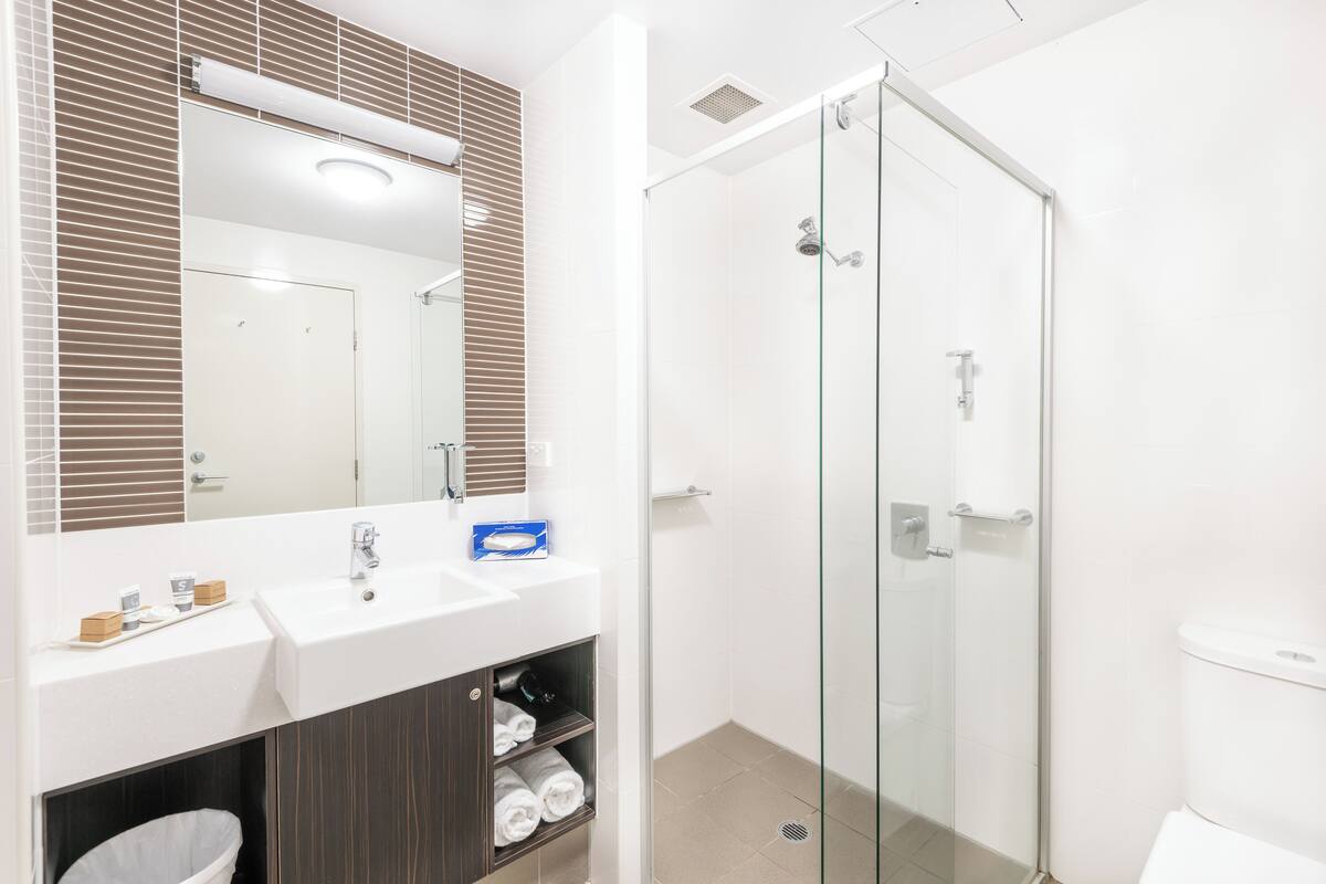 A modern bathroom with a glass shower enclosure, a white sink, and a mirror above the sink.