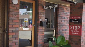 A reception area with a 'Reception' sign, a 'No Reverse Parking' sign, and a 'STOP here to check in' sign.