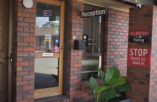 A reception area with a 'Reception' sign, a 'No Reverse Parking' sign, and a 'STOP here to check in' sign.