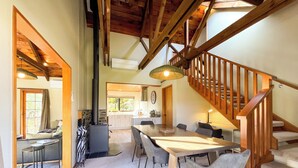 A spacious dining area with a wooden table and chairs, a staircase, and a view of the kitchen in the background. - Glenorchy Lake House (Glenorchy)