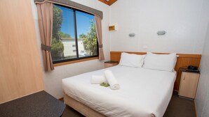 A hotel room with a bed, a nightstand, a desk, and a window with curtains. - Big4 Shepparton Park Lane (Kialla)