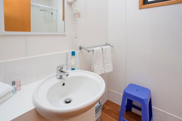 A bathroom with a white sink, a mirror, a towel rack, and a blue stool. - Big4 Shepparton Park Lane (Kialla)