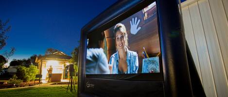 A large outdoor movie screen displaying a film scene.