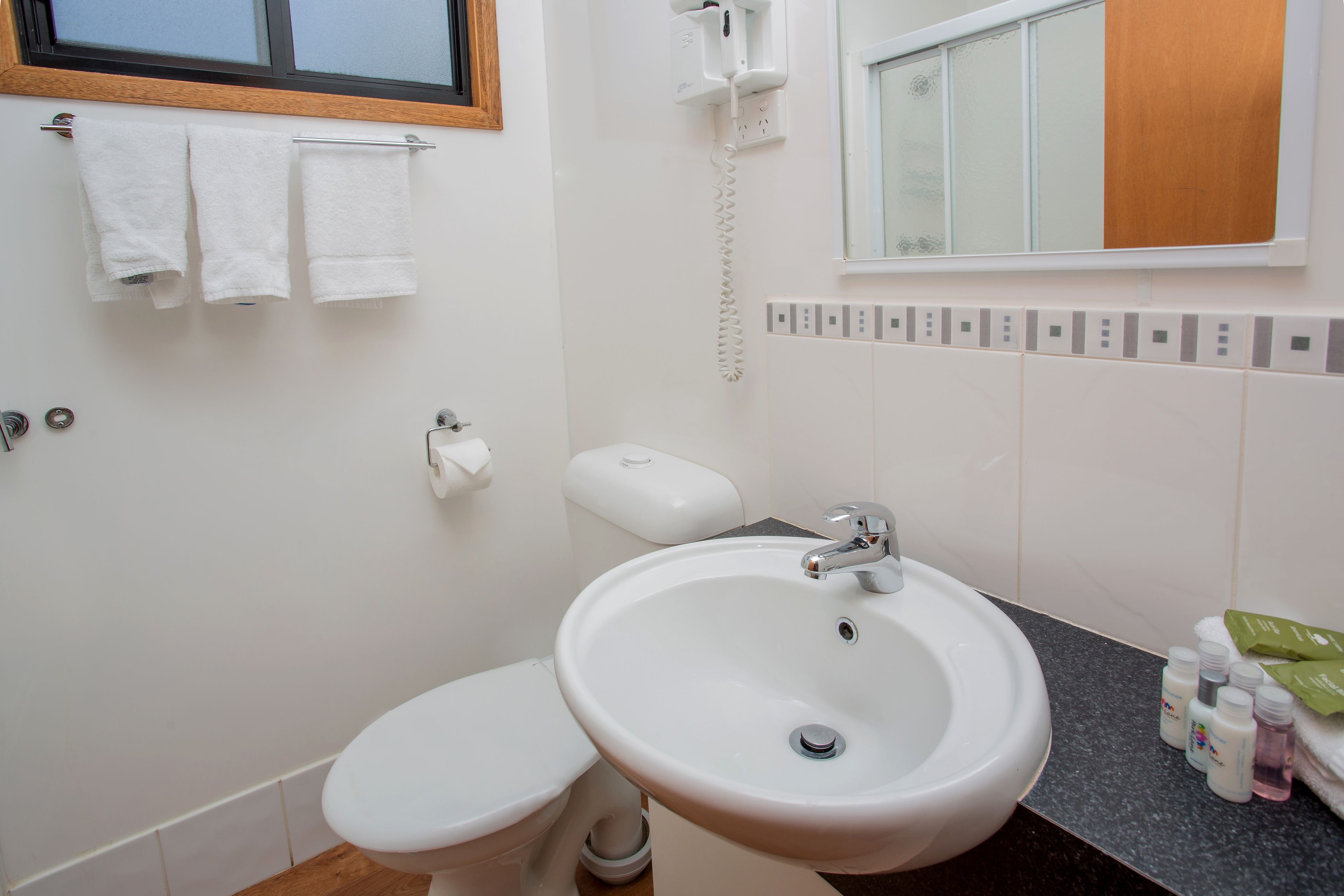Un baño con inodoro, lavamanos y perchero para toallas.