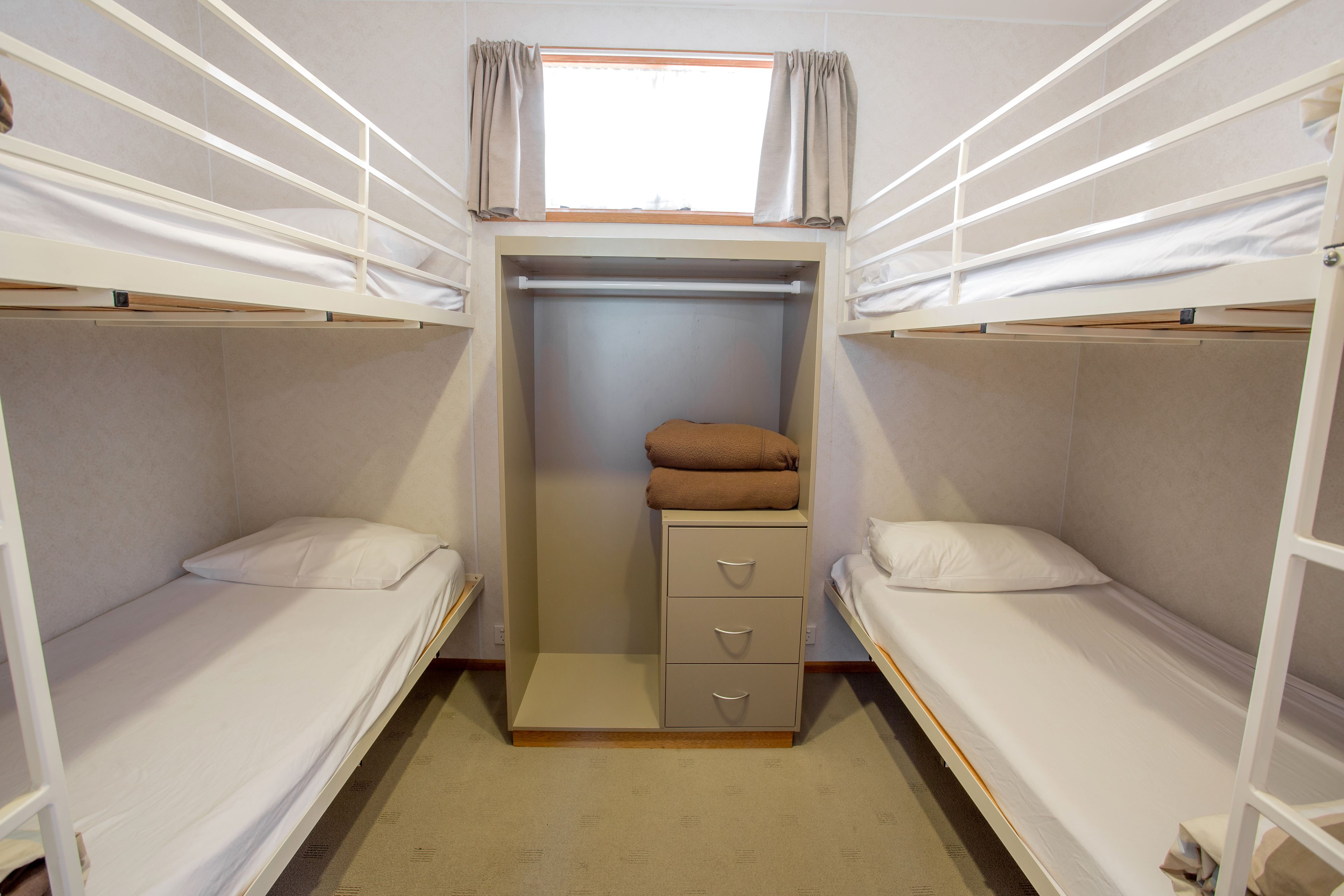 A bunk bed room with a wardrobe and a window.
