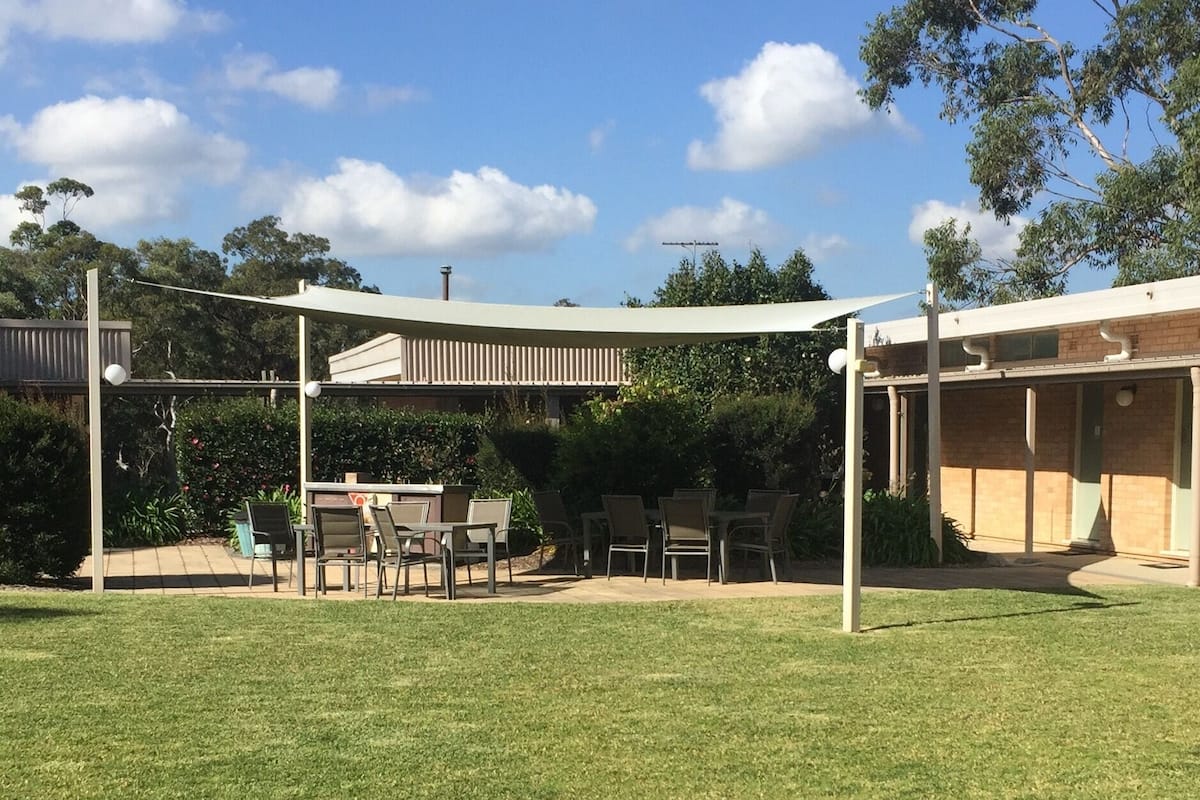 An outdoor patio area with a covered seating area, a table, and chairs.