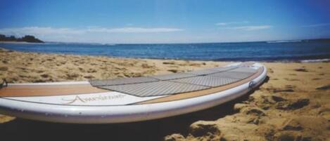 A surfboard on a sandy beach with a clear sky.