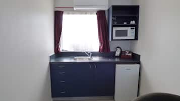 Una cocina compacta con microondas integrado, un lavabo y un refrigerador.