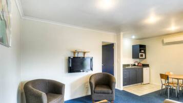 Een knus woongedeelte met een kitchenette, een wandtelevisie en twee fauteuils.