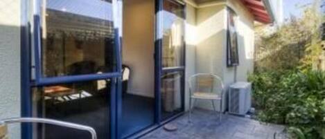A patio with a glass door leading to a room, a chair, and a small table.