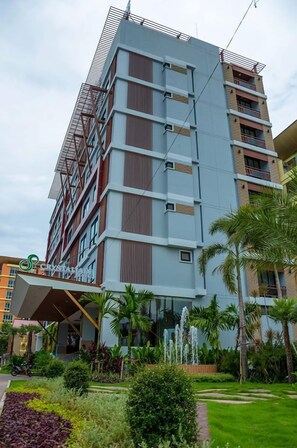 A multi-story hotel with a modern design, featuring a prominent entrance with a covered area and a landscaped garden with palm trees. - Crystal Jade Hotel (Rayong)