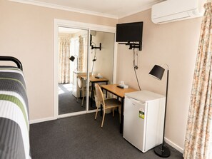 A hotel room with a bed, a desk, a chair, a television, and a refrigerator. - Ulladulla Harbour Motel (Ulladulla)