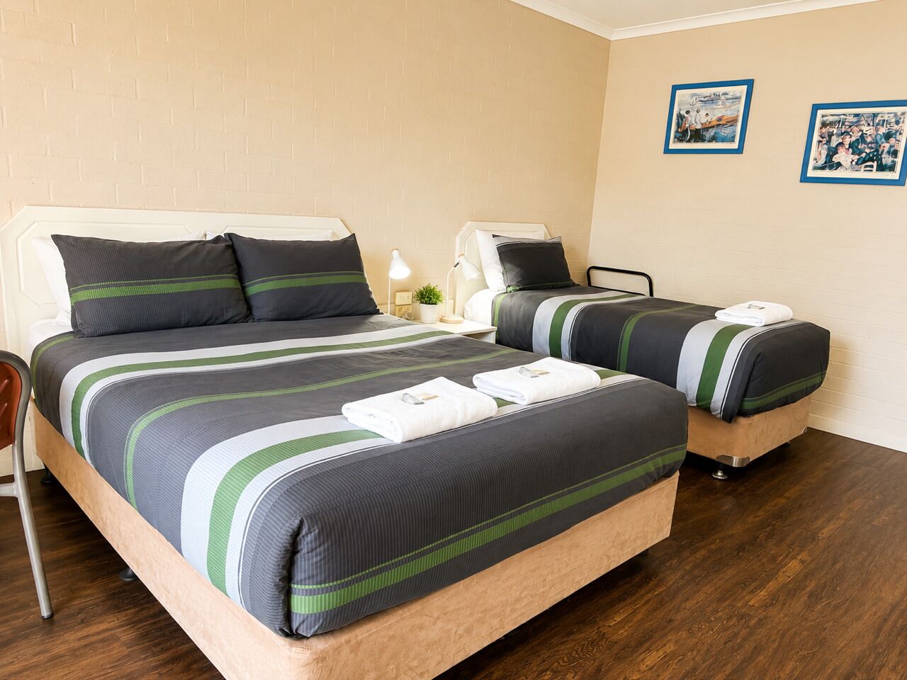 A hotel room with a large bed, a smaller bed, a desk, and a chair.