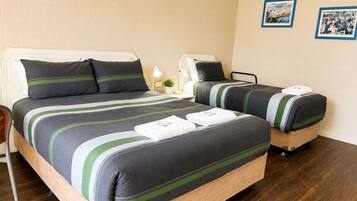 A hotel room with a large bed, a smaller bed, a desk, and a chair.